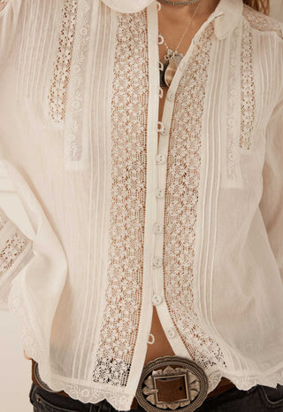 a-close-up-of-a-white-long-sleeve-blouse-with-intricate-lace-panels-and-vertical-pleated-detailing-styled-with-a-large-silver-concho-belt-and-necklace