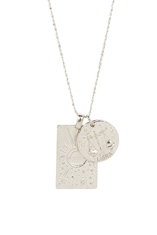 close-up-front-view-of-spell-s-libra-stargazer-zodiac-necklace-charms-one-charm-is-of-a-rectangular-shape-and-features-a-sun-with-stars-while-the-other-charm-is-circular-and-features-the-zodiac-label-and-icon
